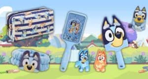 A collection of children's toys and accessories featuring cartoon dogs. Includes a patterned toiletry bag, a hairbrush, a plush toy, and small figurines set against a colorful outdoor background.