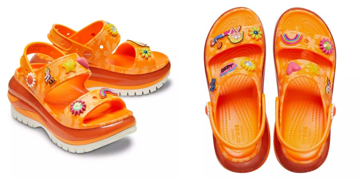 Orange platform sandals adorned with colorful charms, including flowers, a rainbow, and a character with a carrot. The sandals have a textured sole and are shown from both a side and a top view.