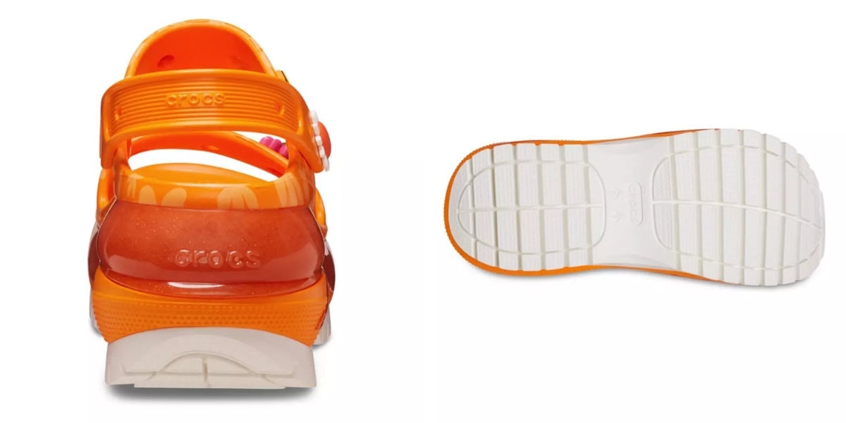 Orange Crocs sandal displaying back view and sole. The shoe features a translucent heel strap and a textured white sole for grip. Branding is visible on the strap and heel area.