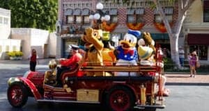Donald Duck, Pluto, and other characters wave from a vintage red fire truck on Disneyland Park's Main Street, U.S.A.