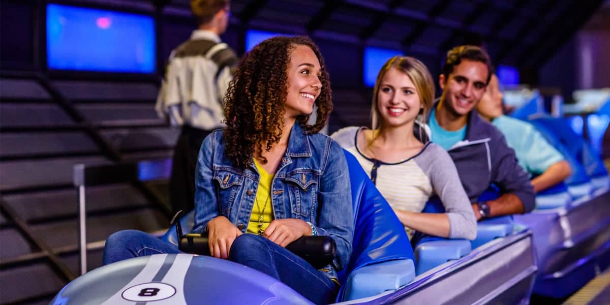 Three people sit side by side in a roller coaster car.
