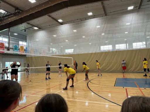 Girls play volleyball on a gym floor finished by Duration Concrete Coatings by Duralast, with teams and fans enjoying the game.