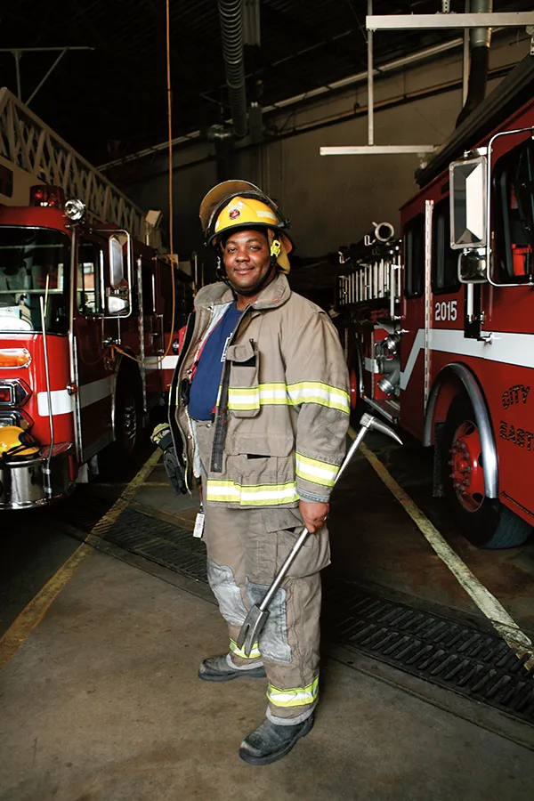 Firefighter in uniform standing between two fire trucks