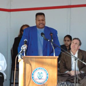 a man standing at a podium with microphones