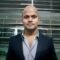 Professional headshot of Devraj in a formal suit, standing in an office environment.
