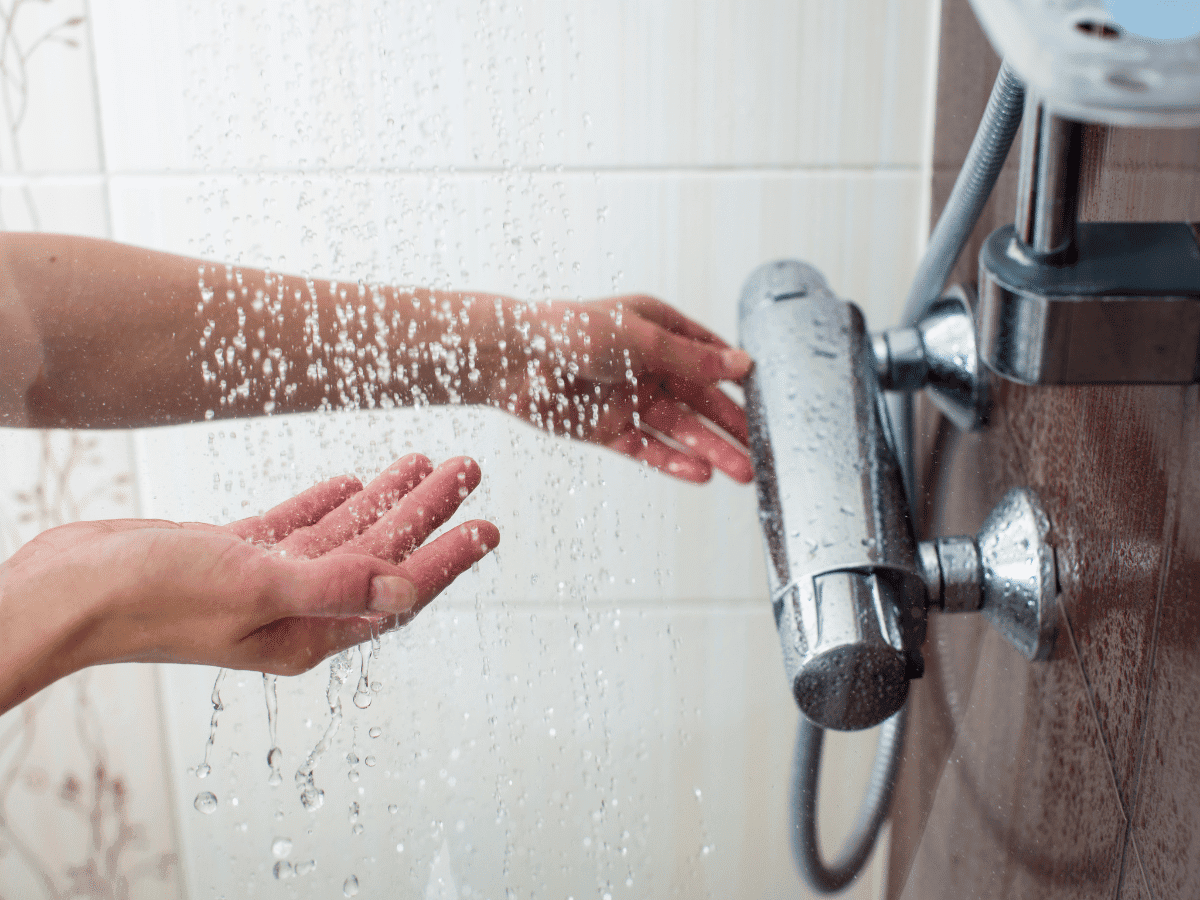 someone running the water in a shower and feeling the temperature of the water