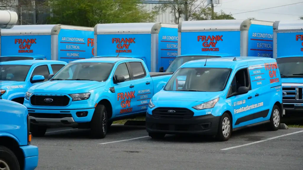Blue service vehicles with "Frank Gay Services" logos are parked in a lot, ready for deployment. Need assistance? Request Service today and let our team handle the rest.