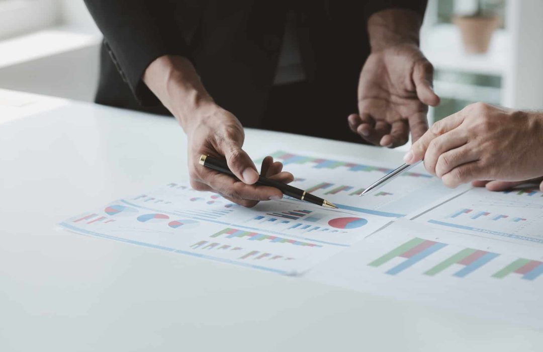 Two businessmen are brainstorming together and reviewing the company financial documents that the fi