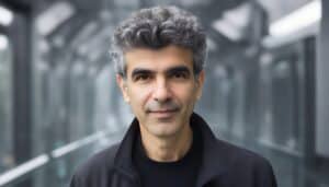 Yoshua Bengio smiling in a grey room, made with Midjourney