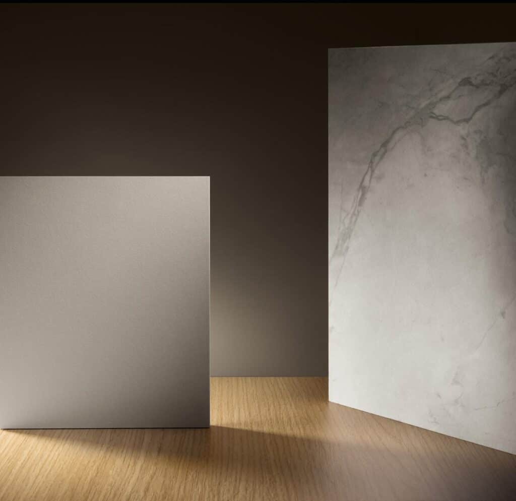 Two stone slabs, one with a smooth gray finish and the other with a marbled texture, on a wooden surface.