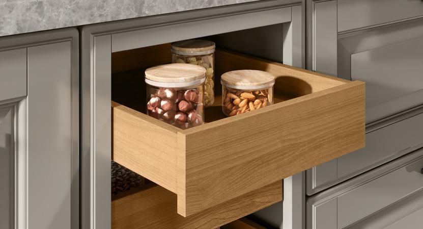 Wooden drawer partially pulled out, holding three glass jars with wooden lids, filled with nuts.