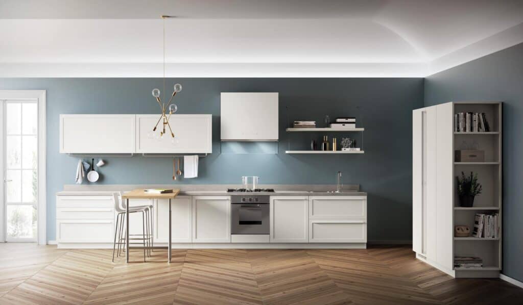 Modern kitchen with white cabinets, a central island with two chairs, and a decorative chandelier, set against a blue wall.