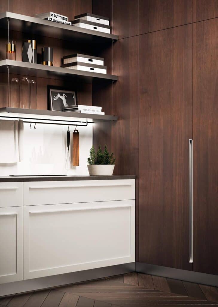 Modern kitchen corner with white cabinetry, dark wood paneling, open shelving, decorative items, and plants.