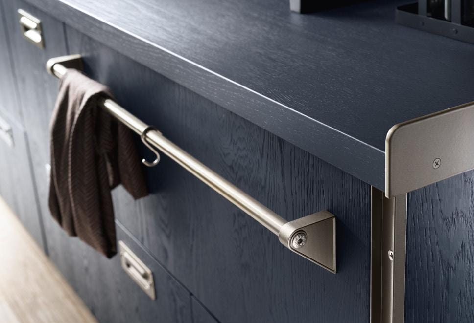 Dark blue kitchen cabinets with a sleek metal railing on the side, holding a brown cloth.
