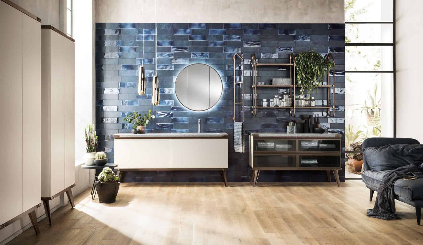 Modern bathroom with a blue tiled accent wall, round mirror, white vanity, and wooden floor.