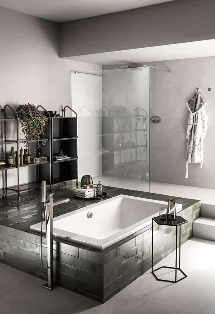 Modern bathroom with a sunken bathtub, glass-enclosed shower, minimalist shelving, and a small side table.