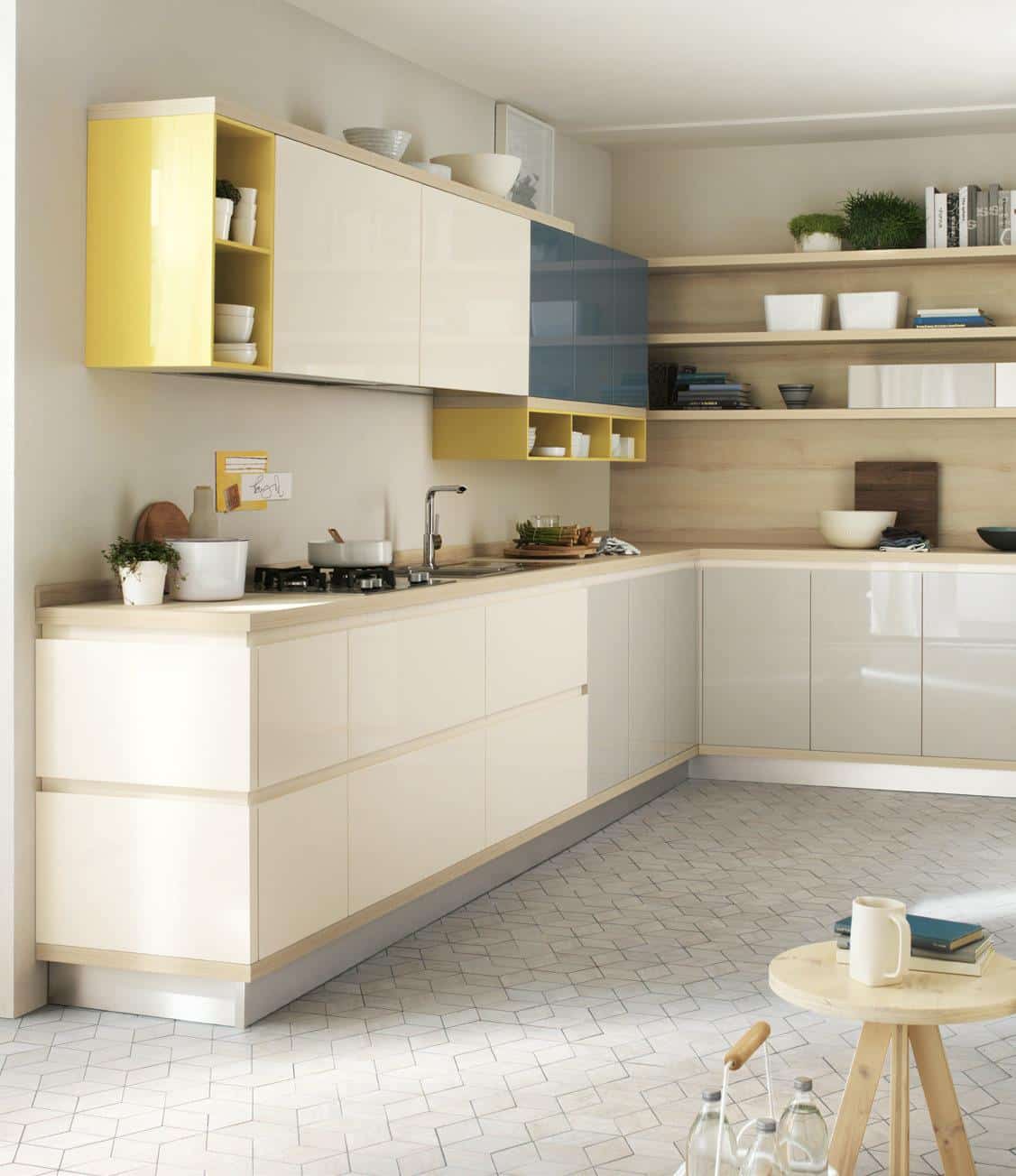Modern kitchen with glossy cabinets in beige, yellow, and blue, wooden countertops, open shelving with dishes and plants, and a geometric-patterned tile floor.