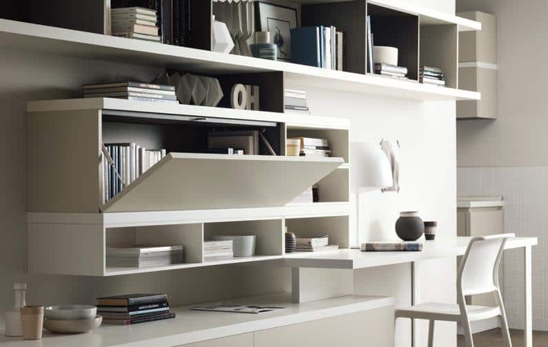 Modern home office with white shelving, books, decorative items, and a desk with a chair.