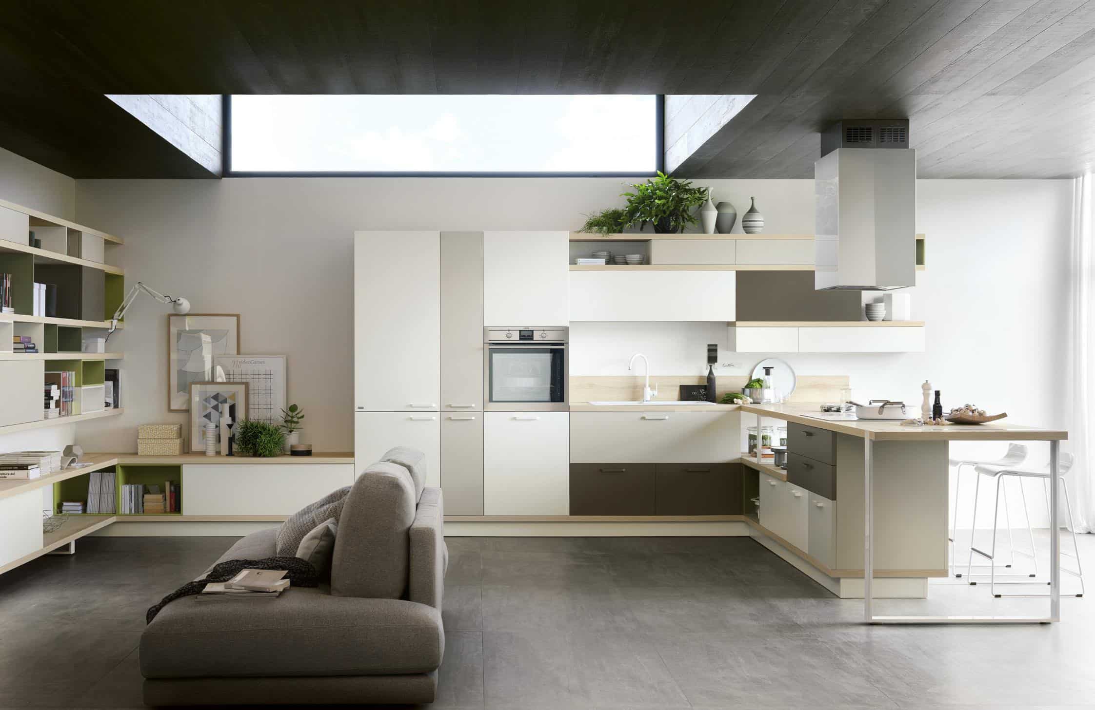 Modern open-plan kitchen and living area with sleek cabinetry, a built-in oven, an island with bar stools, and a gray sofa.