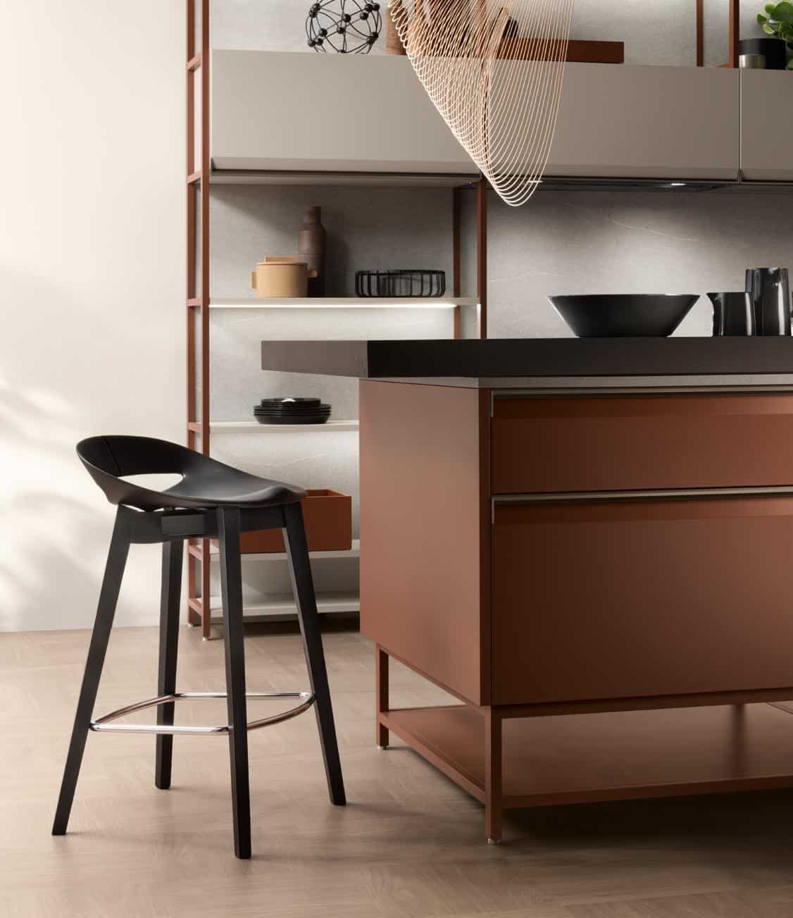 Modern kitchen interior with a black bar stool next to a brown island counter, featuring minimalist shelving and decorative items.