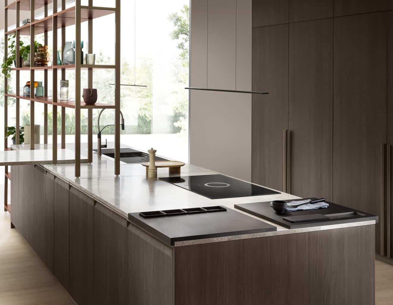 Modern kitchen with sleek cabinetry, an island with a cooktop, marble countertops, open shelving displaying decorative items, and large glass windows providing natural light.