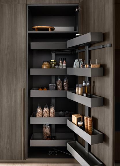 Tall kitchen pantry with pull-out shelves, containing various jars, bottles, and food items.