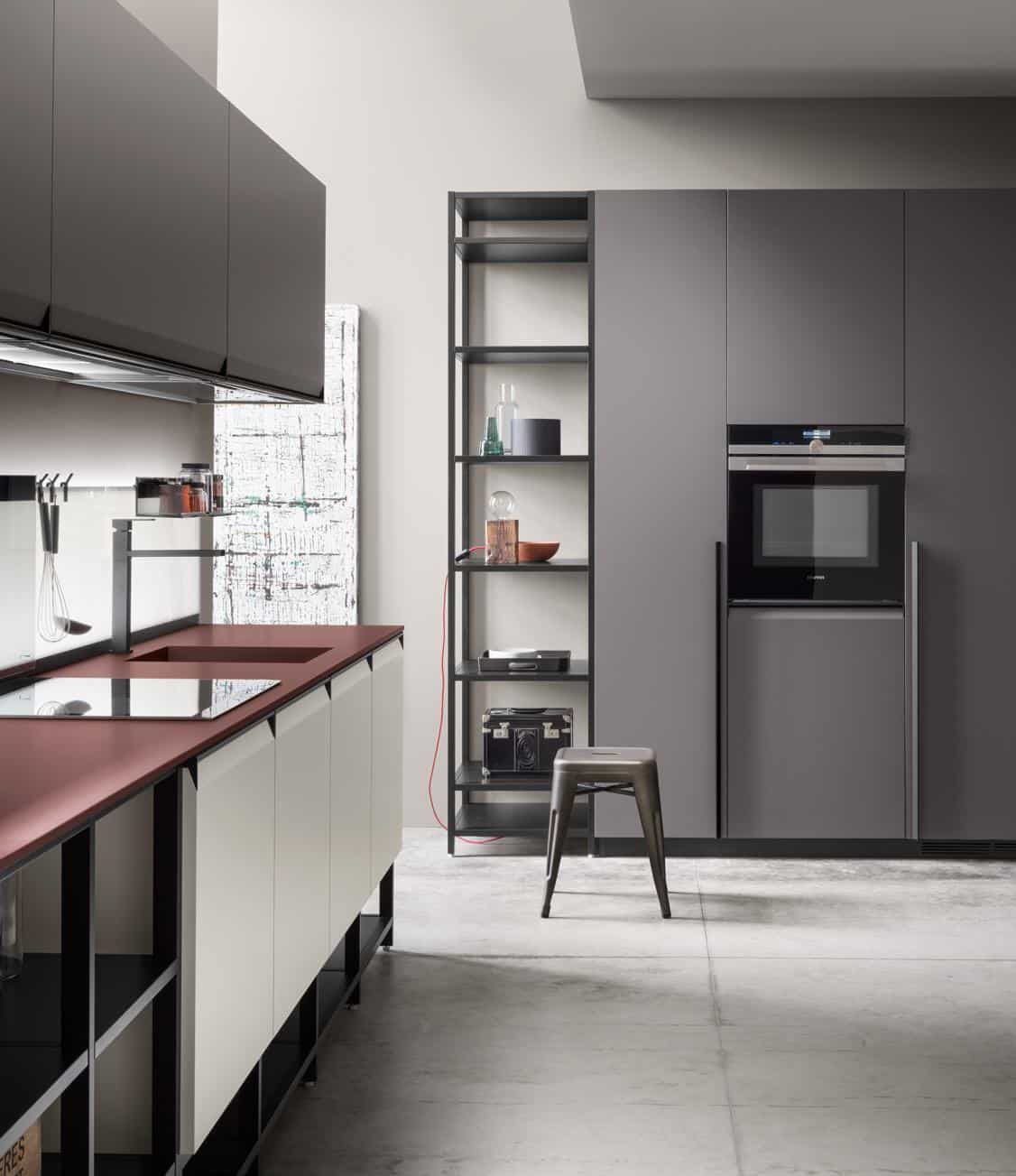 Modern kitchen interior with matte gray cabinets, a dark red countertop, and minimalist shelving.