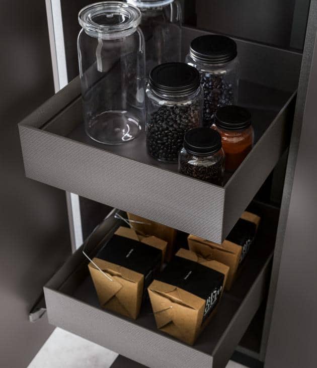 Open pantry drawers containing glass jars with black lids and brown paper food boxes.