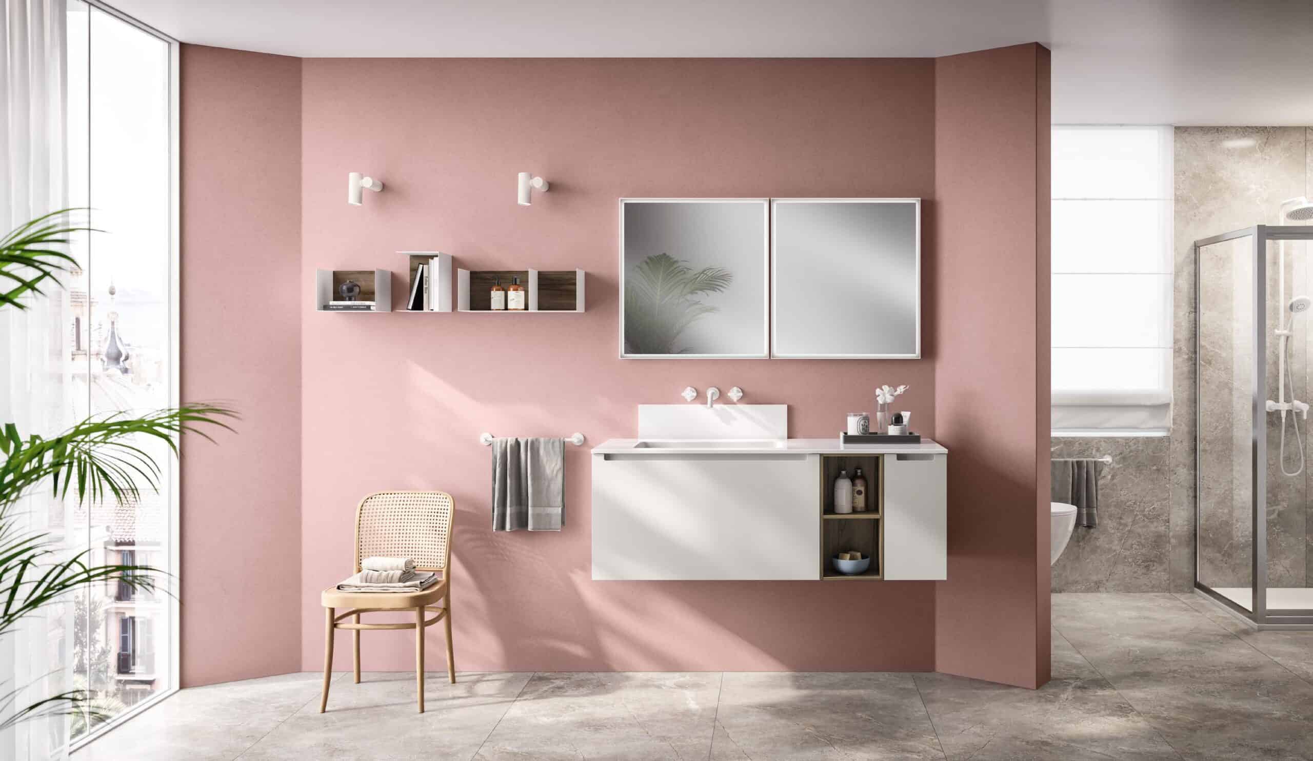 Modern bathroom with pink walls, a floating white vanity, wall-mounted shelves, a mirror, a rattan chair, large window, and a glass-enclosed shower.