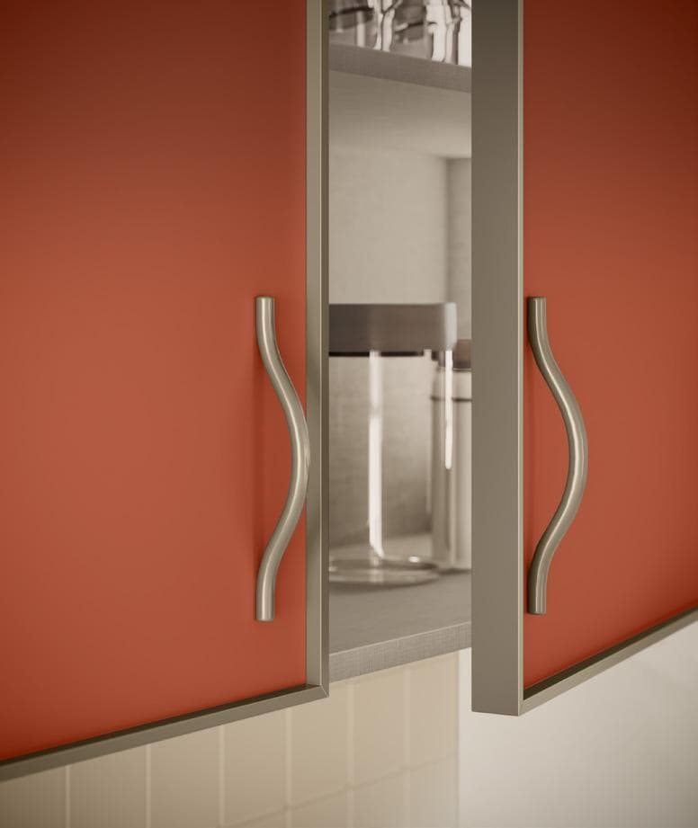 Close-up view of an open kitchen cabinet with orange doors and curved silver handles, revealing glass jars inside.