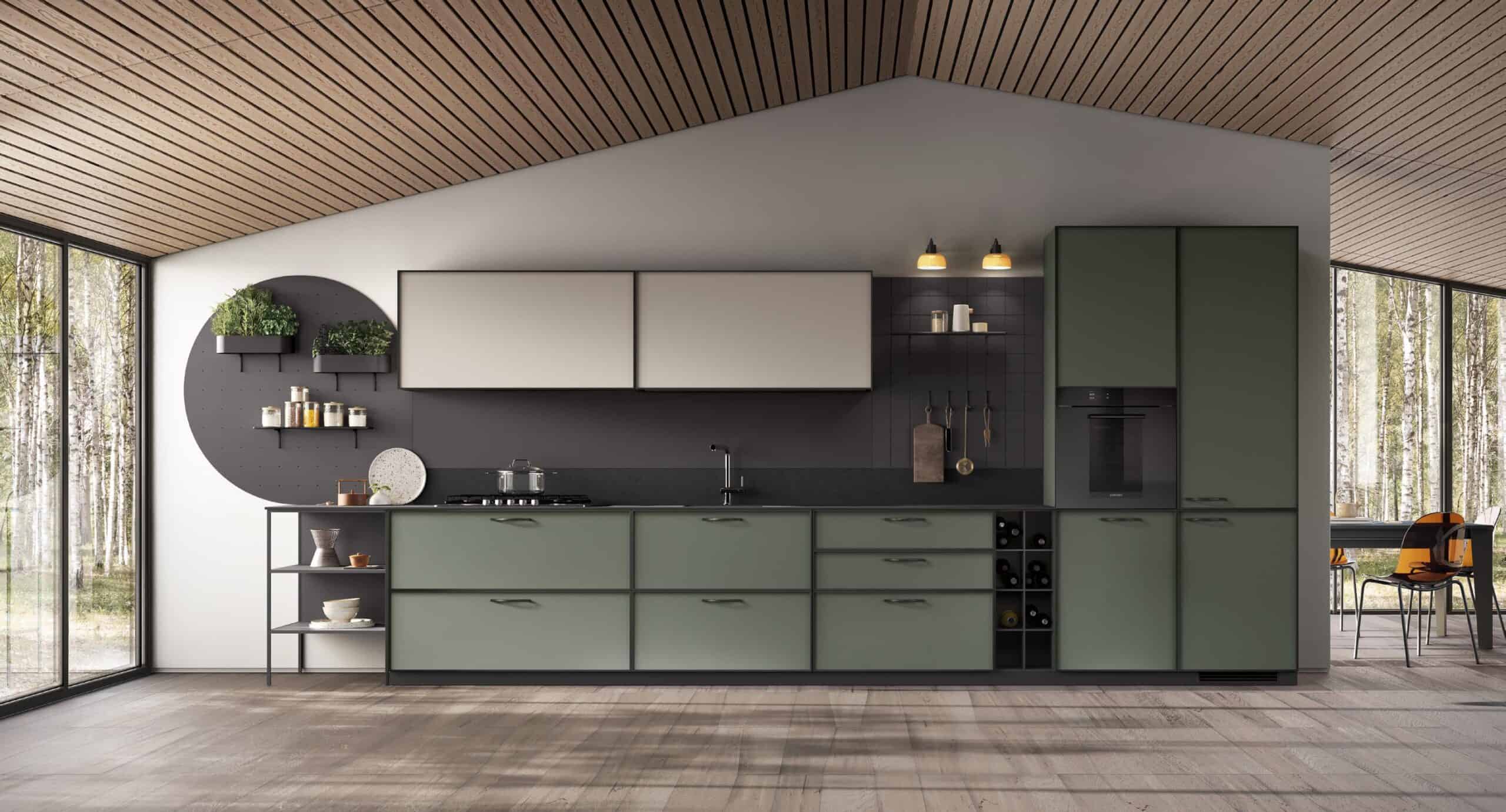 Modern kitchen with green cabinets, black countertop, ceiling lights, and large windows overlooking birch trees.