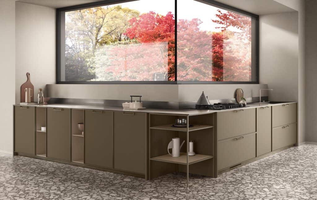 Modern kitchen with olive green cabinets, a stainless steel countertop, and a gas stove. Large window with a view of vibrant autumn foliage. Terrazzo flooring.