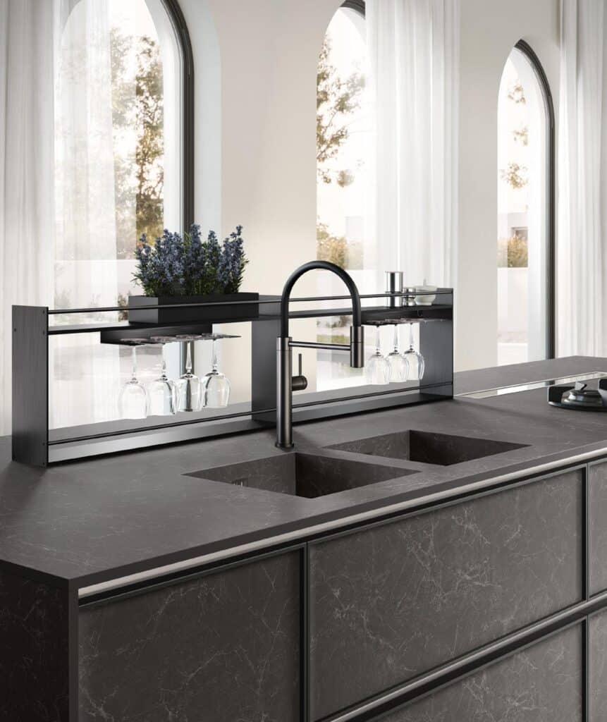 Modern kitchen with dark marble countertops, double sink, black faucet, and overhead glass rack.