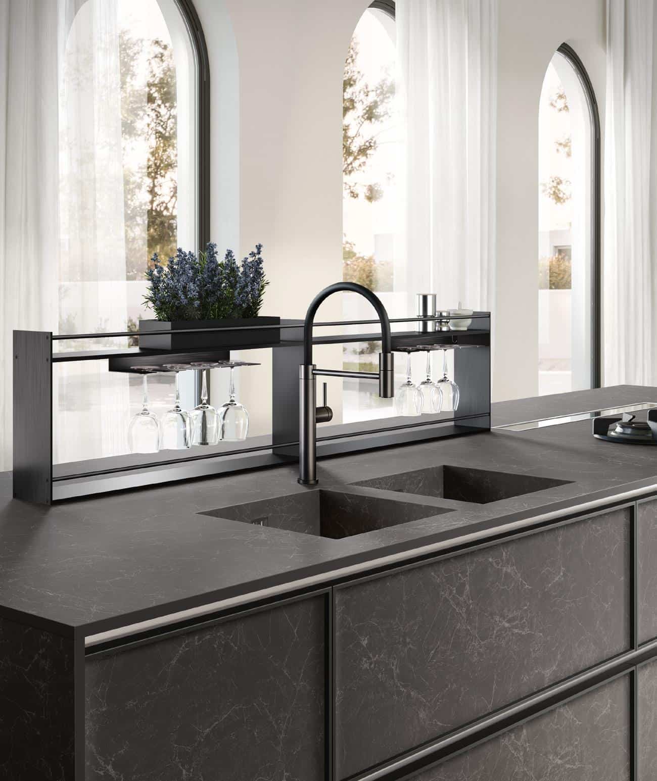 Modern kitchen with dark marble countertops, double sink, black faucet, and overhead glass rack.