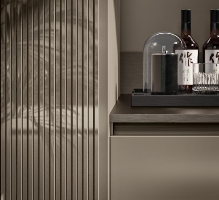 Modern cabinet with vertical grooves, three bottles with Japanese labels, a glass, and a cylindrical container under a glass dome on a countertop.