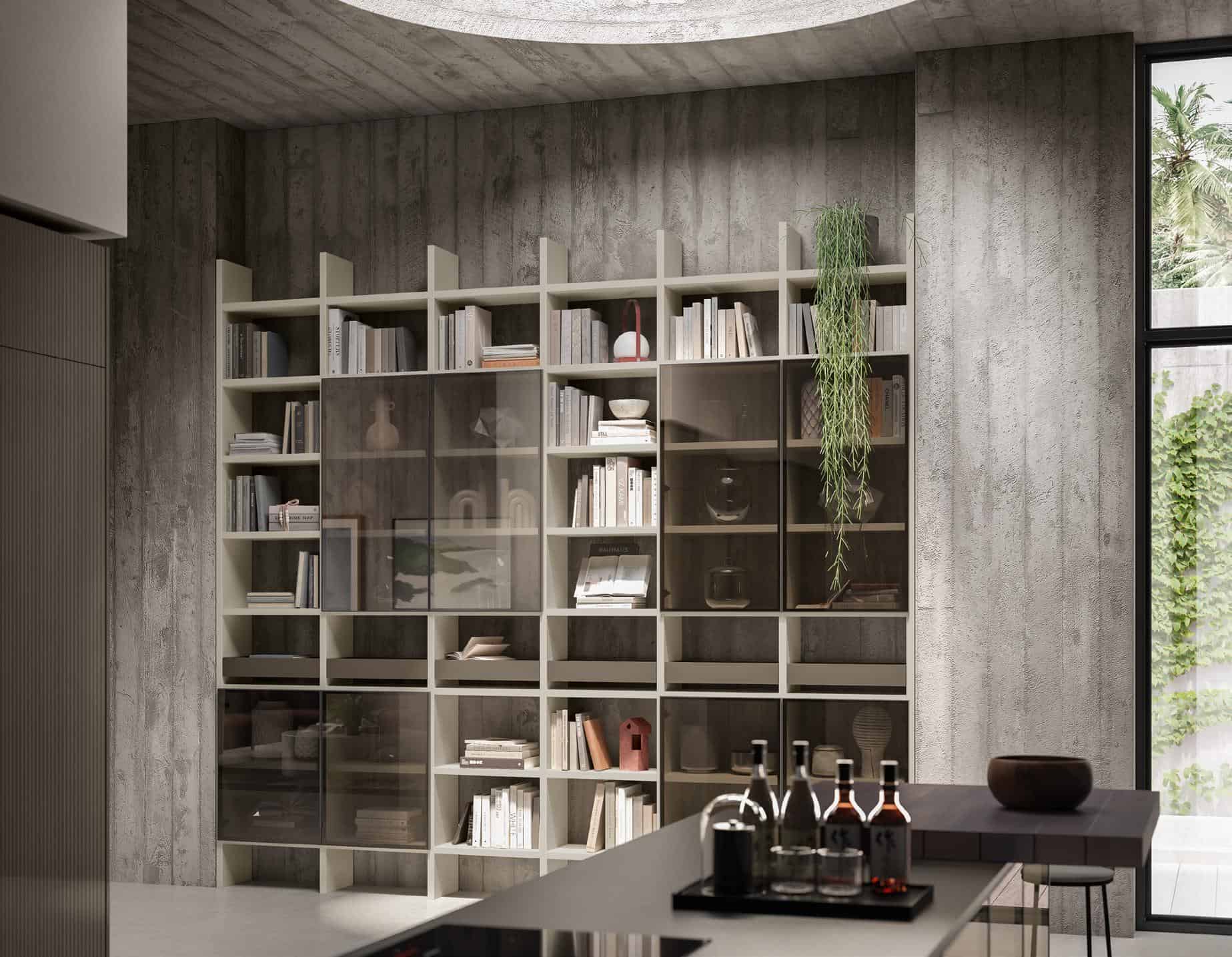 Modern interior with a large bookshelf against a concrete wall, containing books, decorative items, and a hanging plant; a kitchen counter with bottles and glassware in the foreground, and a window with a view of greenery.