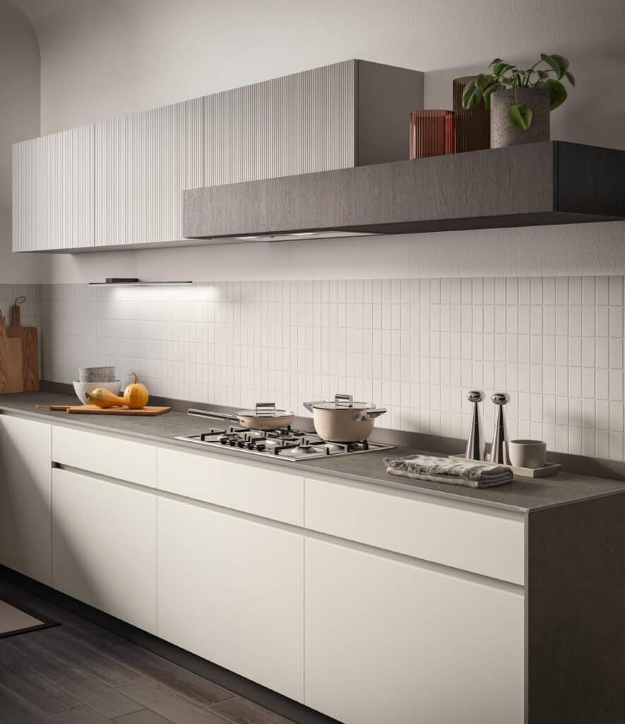 Modern kitchen with white cabinets, a gray countertop, a gas stovetop with a pot, and decor items including a plant and bowls.