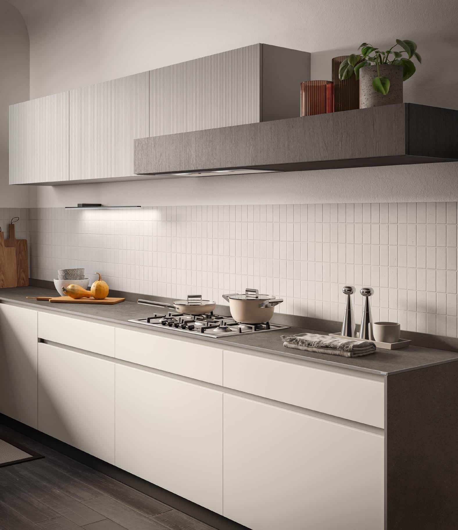 Modern kitchen with white cabinets, a gray countertop, a gas stovetop with a pot, and decor items including a plant and bowls.