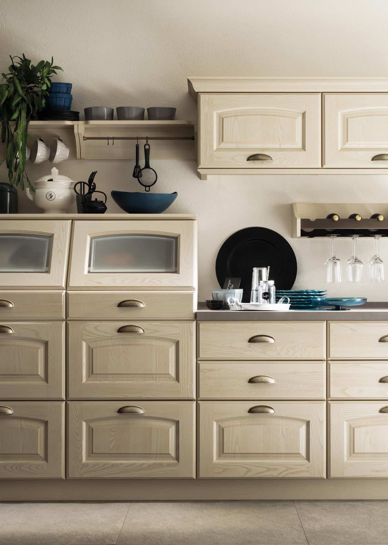 Wooden kitchen cabinets with decorative bowls, plates, and glasses arranged on the countertop and shelves.