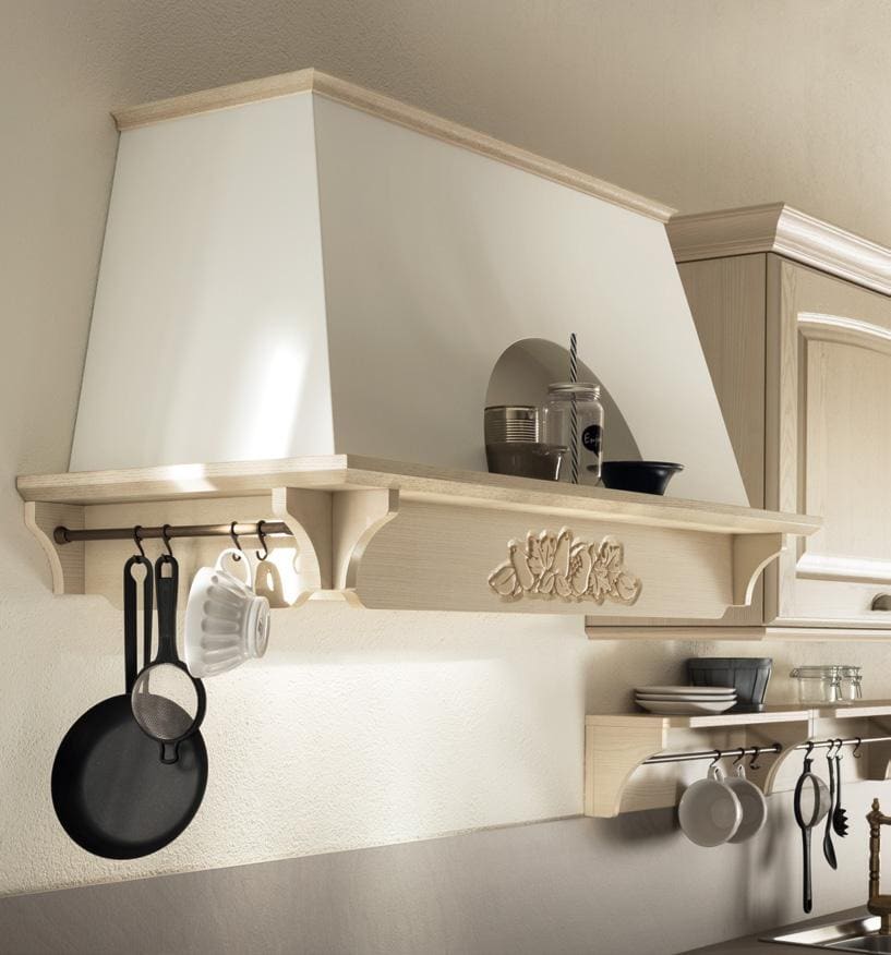 A classic-style kitchen range hood with decorative molding, featuring hanging utensils and a small shelf with jars and a bowl on top.
