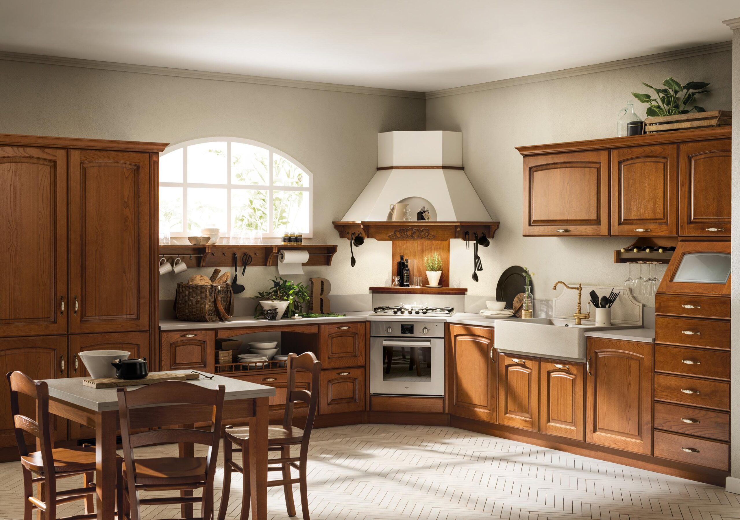 Rustic kitchen with wooden cabinets, a white range hood, arched window, and a wooden dining table with chairs.