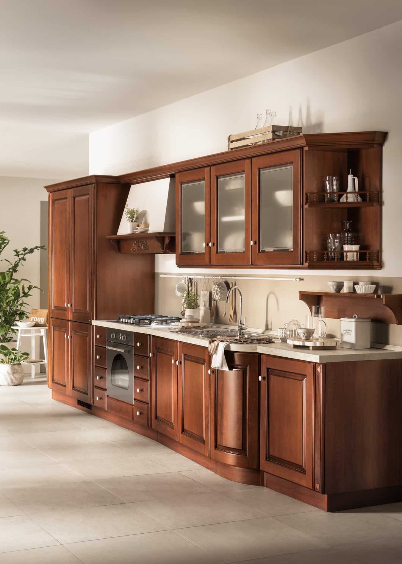 Traditional wooden kitchen cabinets with glass-panel doors, countertop, sink, oven, stove, and decorative shelves.