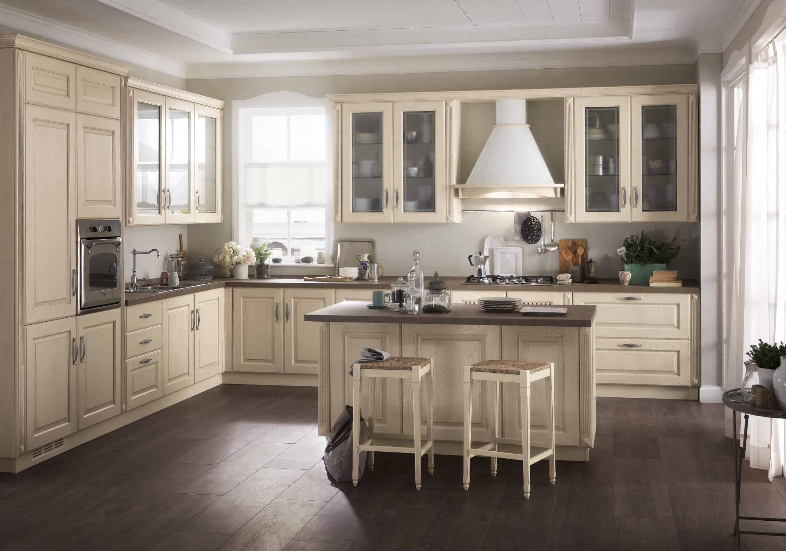Spacious kitchen with cream-colored cabinets, a central island with two stools, and dark wooden flooring.