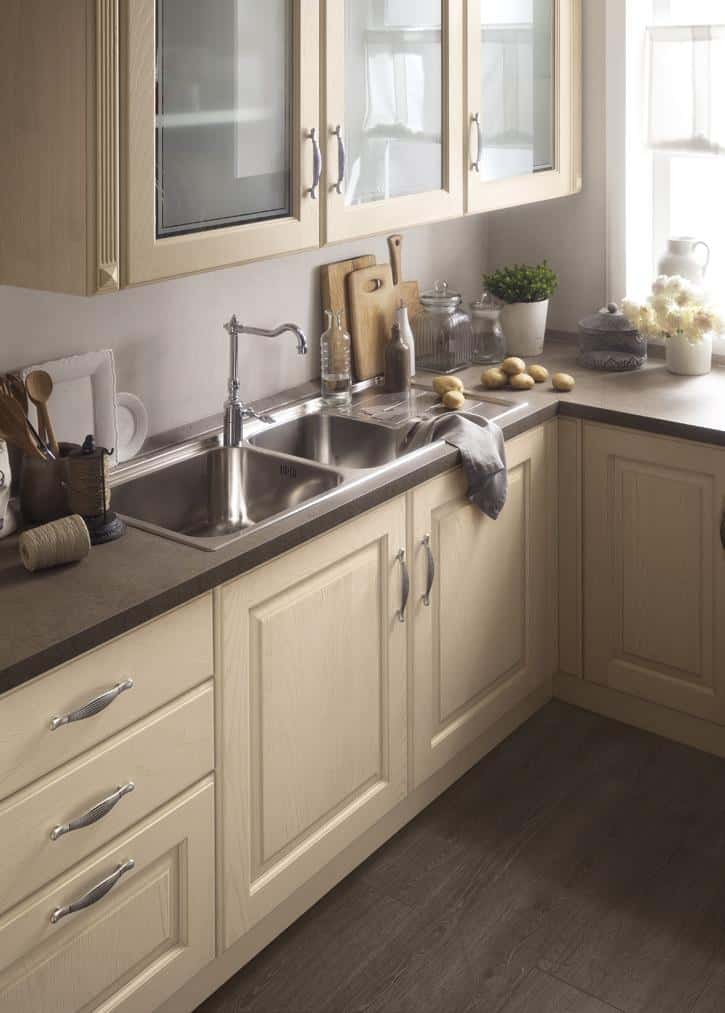 Modern kitchen with light wooden cabinets, dark countertop, and a stainless steel double sink.
