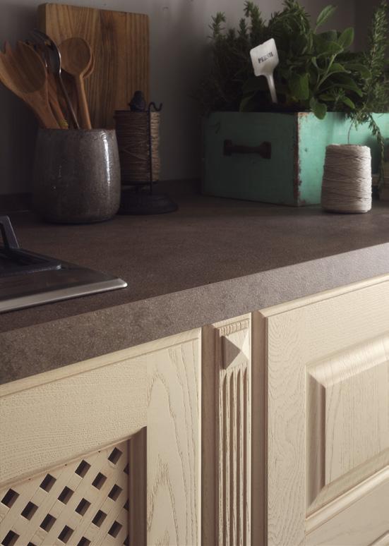 Kitchen counter with a wooden cabinet, utensil holder, cutting board, spool of twine, and a planter box with herbs.