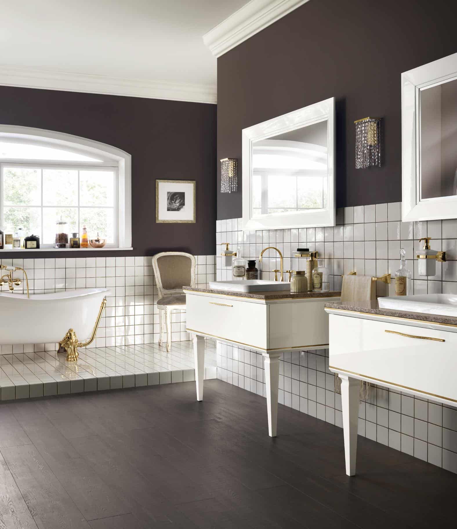 Elegant bathroom with a freestanding bathtub, gold fixtures, wall-mounted sinks, large mirrors, and dark wood flooring.