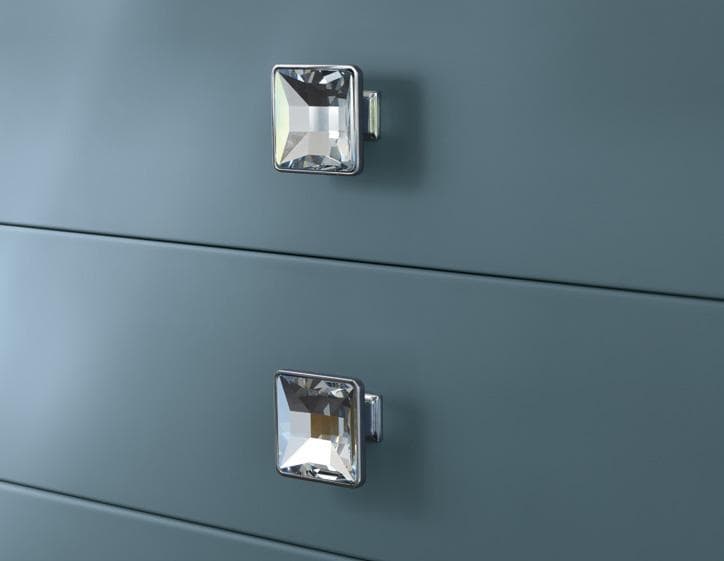 Close-up of two square crystal drawer knobs on a blue surface.