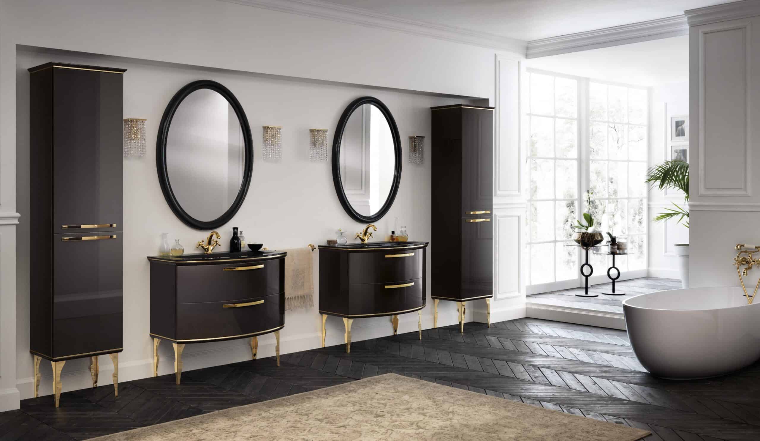 Luxurious bathroom interior with dark cabinets, gold accents, oval mirrors, and a freestanding bathtub near large windows with natural light.