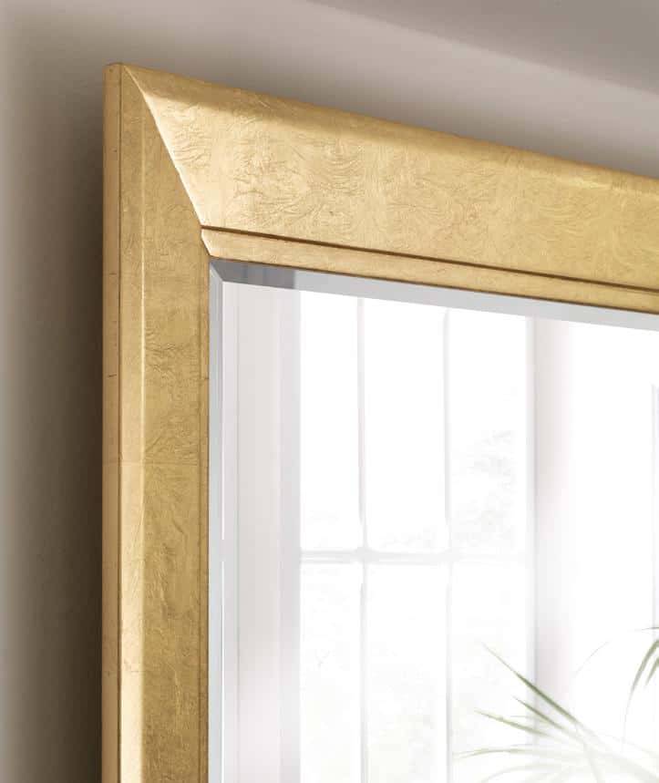 Close-up of a corner of a large mirror with a gold frame and a reflection of a window.