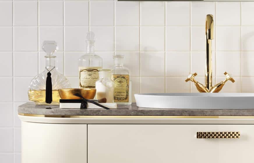 Elegant bathroom vanity with a gold faucet, glass bottles, and decorative items on a countertop.
